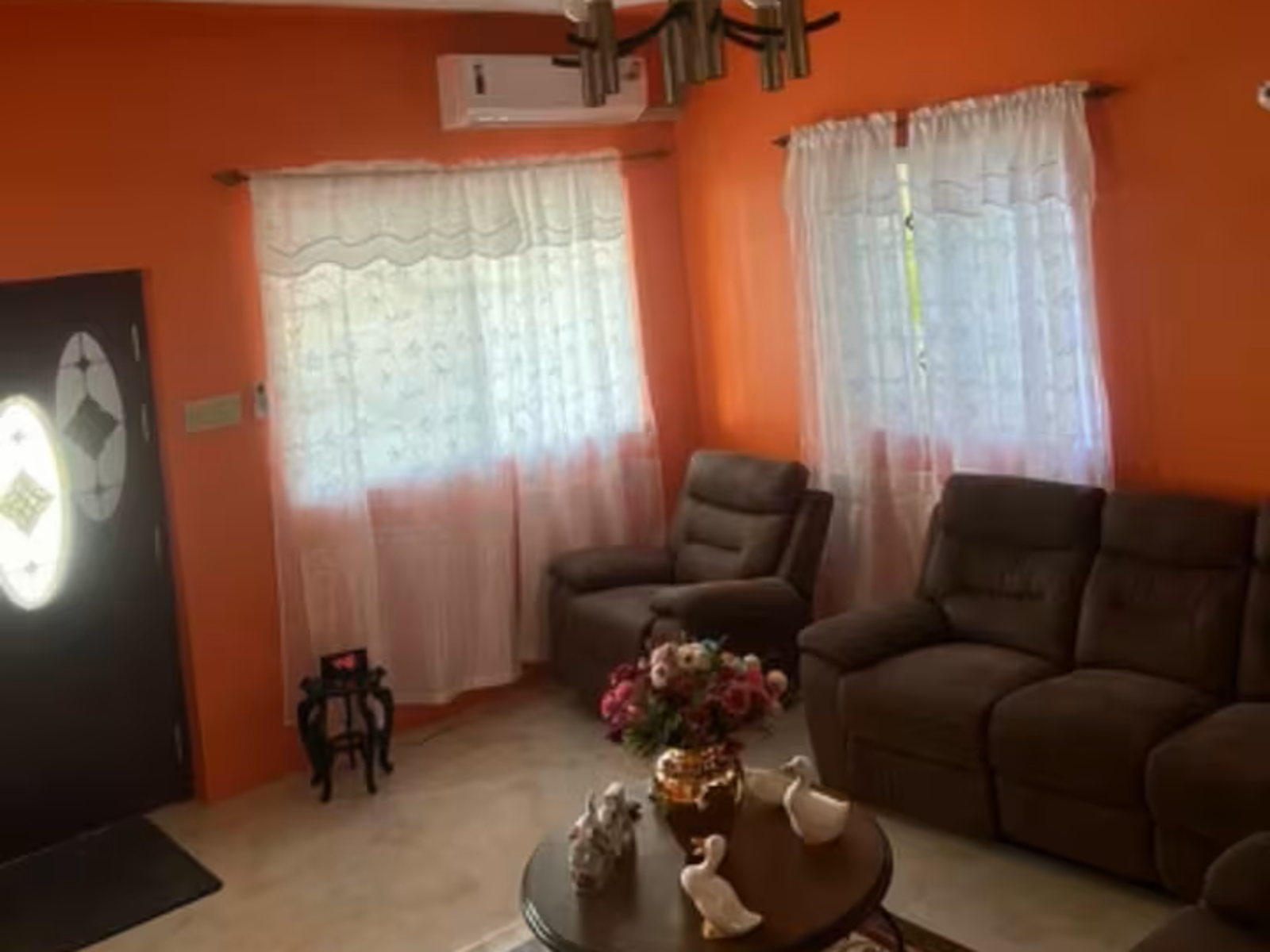 Spacious light-green guest room with two double beds and balcony ocean view.