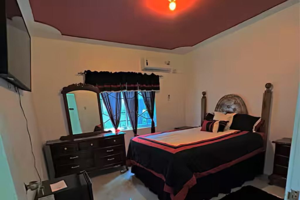 Elegant red master suite with king bed, private balcony, and panoramic Caribbean ocean view